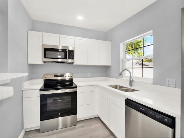 kitchen with light hardwood / wood-style flooring, sink, appliances with stainless steel finishes, and white cabinetry