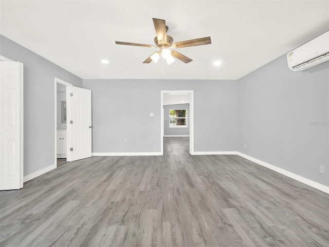 spare room featuring light hardwood / wood-style flooring, ceiling fan, and a wall unit AC