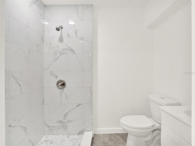 bathroom with tiled shower, vanity, toilet, and tile patterned floors