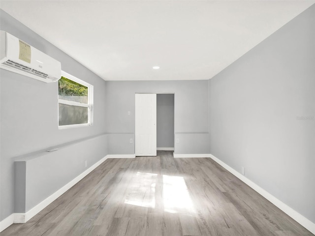 spare room with light wood-type flooring and a wall mounted AC