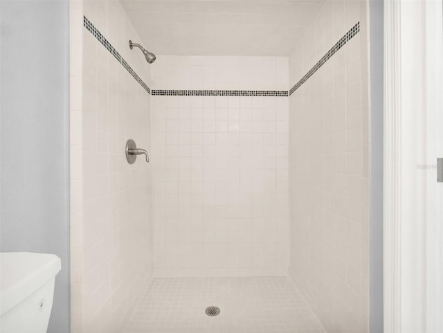 bathroom featuring toilet and a tile shower