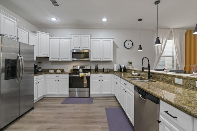 kitchen with dark stone countertops, white cabinetry, appliances with stainless steel finishes, and sink