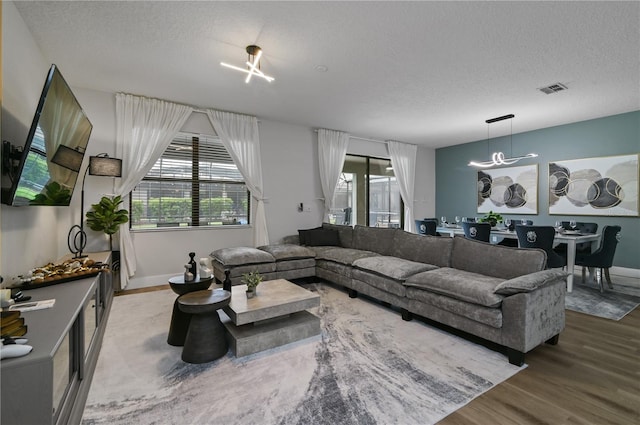 living room featuring a textured ceiling, wood-type flooring, and an inviting chandelier