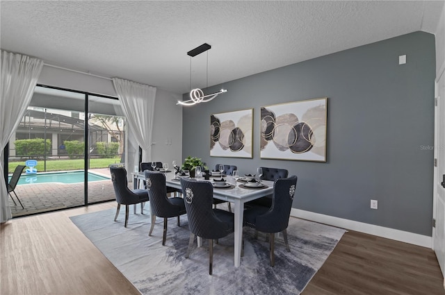 dining space with wood-type flooring and a textured ceiling