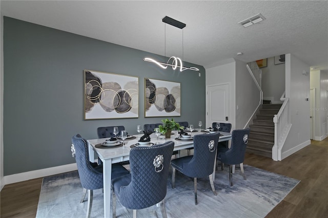 dining area with an inviting chandelier, a textured ceiling, and dark hardwood / wood-style floors