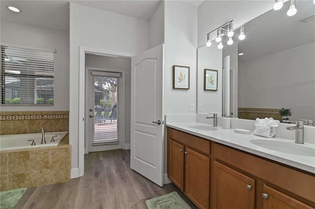 bathroom featuring vanity, tiled bath, and hardwood / wood-style floors