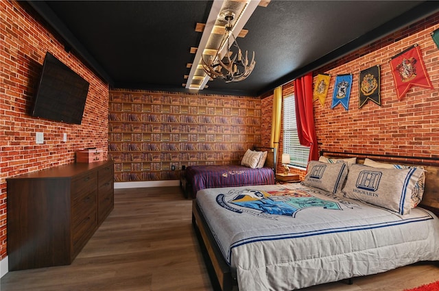 bedroom with a textured ceiling, wood-type flooring, and brick wall