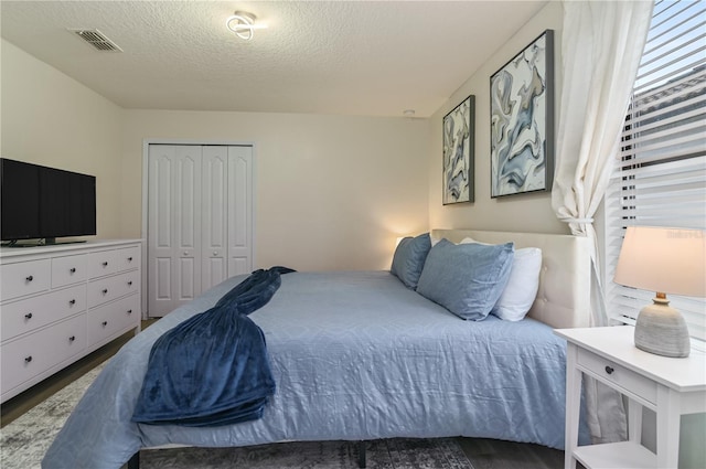 bedroom featuring a textured ceiling, dark hardwood / wood-style flooring, and a closet