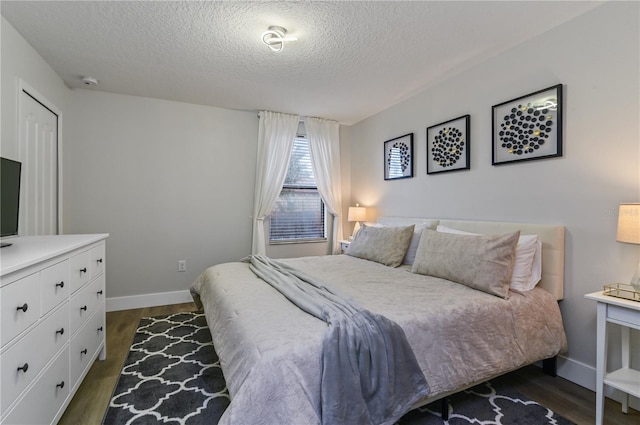 bedroom with a textured ceiling and dark hardwood / wood-style flooring