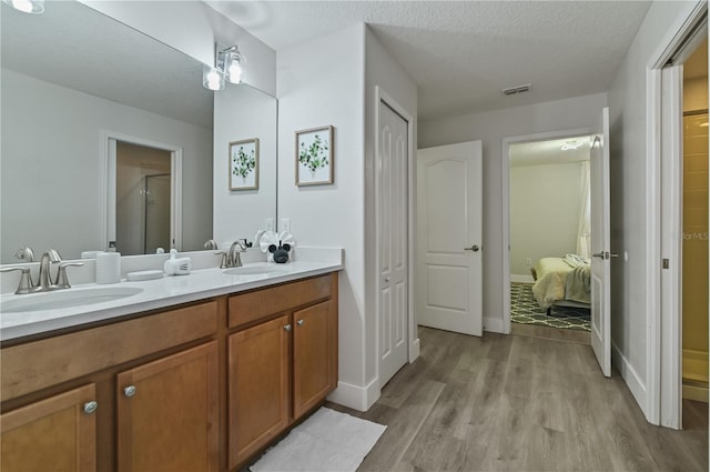 bathroom featuring hardwood / wood-style floors, a textured ceiling, an enclosed shower, and vanity