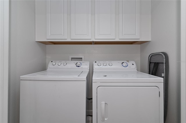 clothes washing area featuring washing machine and clothes dryer and cabinets