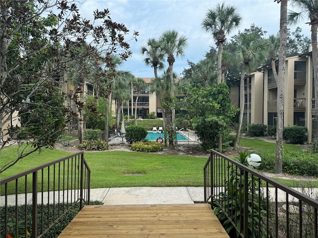 wooden deck with a yard and a community pool