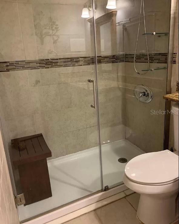 bathroom with tile patterned floors, toilet, an enclosed shower, and vanity