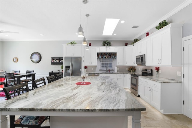 kitchen with an island with sink, appliances with stainless steel finishes, and pendant lighting