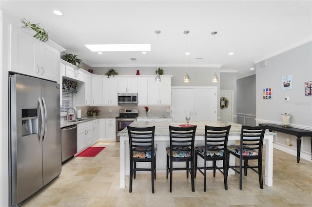 kitchen with a breakfast bar, stainless steel appliances, white cabinets, a center island with sink, and decorative light fixtures