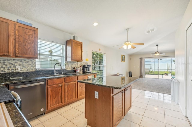 kitchen featuring ceiling fan, sink, backsplash, dishwasher, and a center island