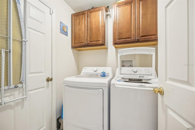 laundry room featuring cabinets, a textured ceiling, and washing machine and clothes dryer