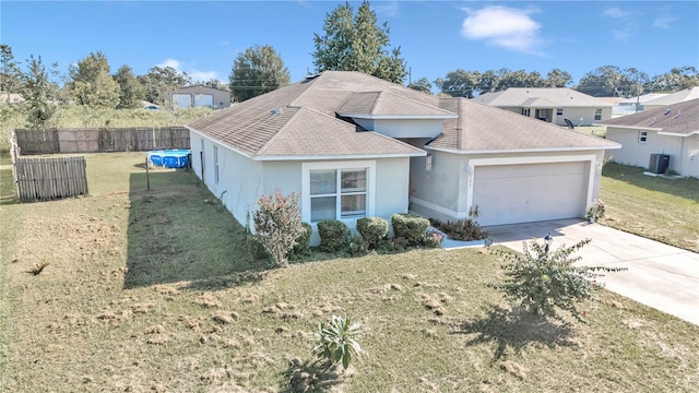 view of front of home featuring a front yard, a garage, and central AC unit