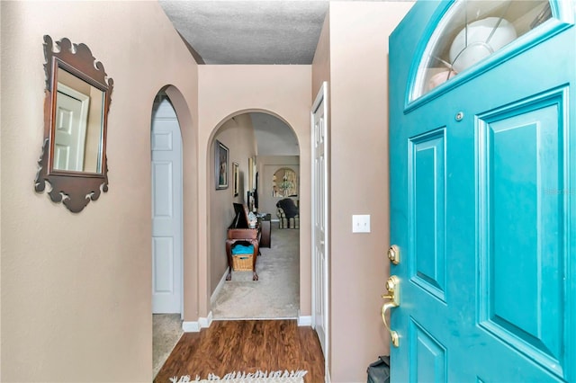 foyer featuring a textured ceiling and dark wood-type flooring