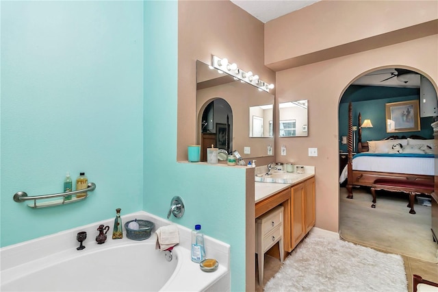 bathroom featuring ceiling fan, a washtub, and vanity