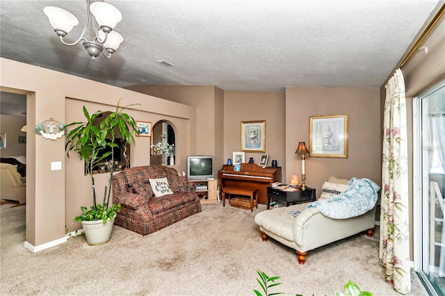 living room featuring carpet flooring, a textured ceiling, an inviting chandelier, and vaulted ceiling