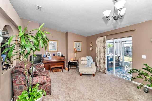 carpeted living room featuring a textured ceiling and a notable chandelier