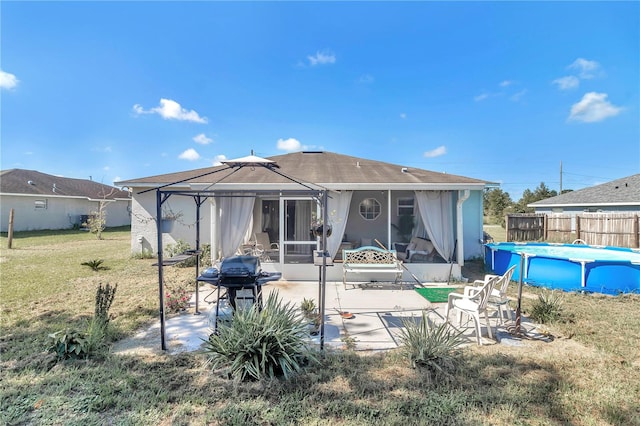 rear view of house featuring a lawn, a sunroom, a fenced in pool, and a patio