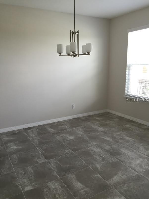 unfurnished room featuring an inviting chandelier