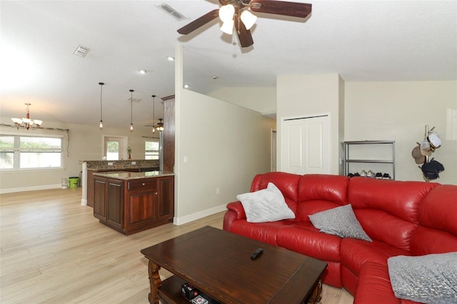 living room featuring ceiling fan with notable chandelier, lofted ceiling, and light hardwood / wood-style floors