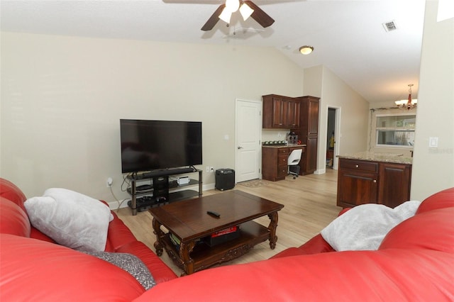 living room with lofted ceiling, light hardwood / wood-style flooring, and ceiling fan with notable chandelier