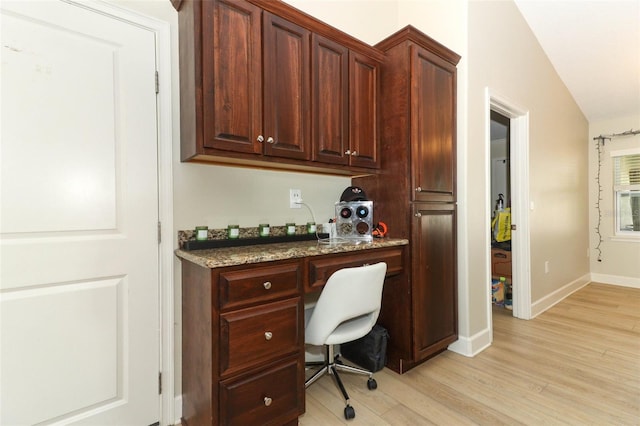 office area with vaulted ceiling, built in desk, and light hardwood / wood-style flooring