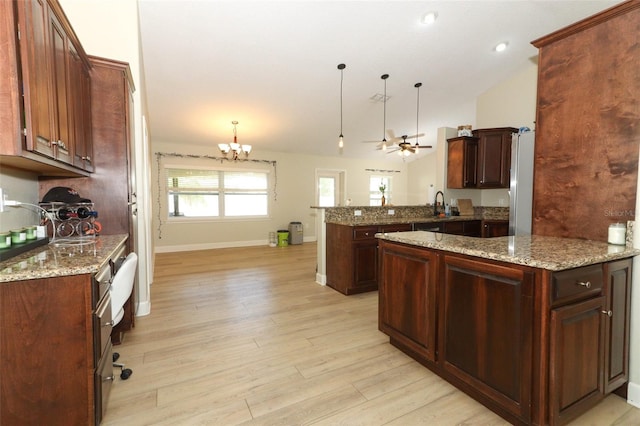 kitchen with lofted ceiling, pendant lighting, kitchen peninsula, and light hardwood / wood-style flooring