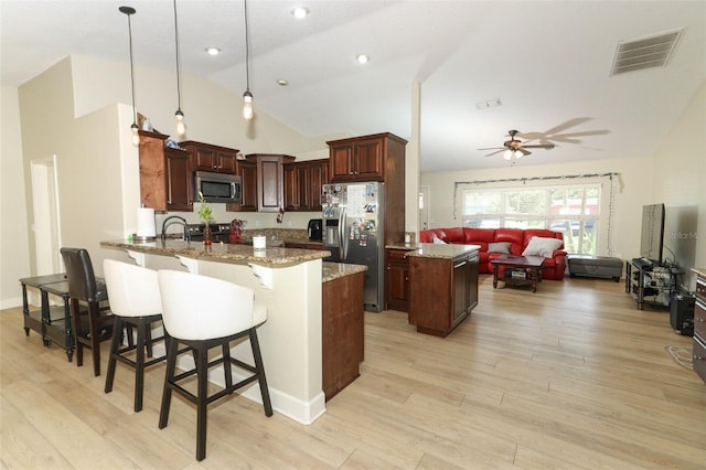 kitchen featuring light hardwood / wood-style flooring, stainless steel appliances, ceiling fan, kitchen peninsula, and pendant lighting