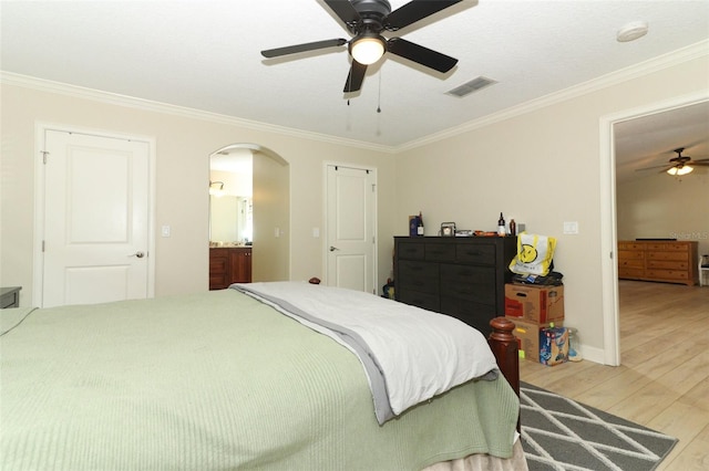 bedroom featuring ceiling fan, hardwood / wood-style flooring, ensuite bathroom, and ornamental molding