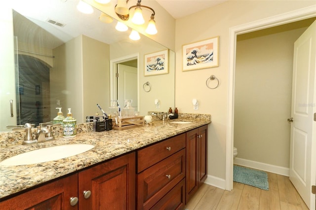 bathroom with a shower with door, vanity, toilet, and wood-type flooring