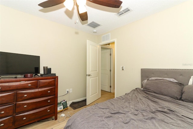 bedroom with a textured ceiling, light hardwood / wood-style flooring, and ceiling fan