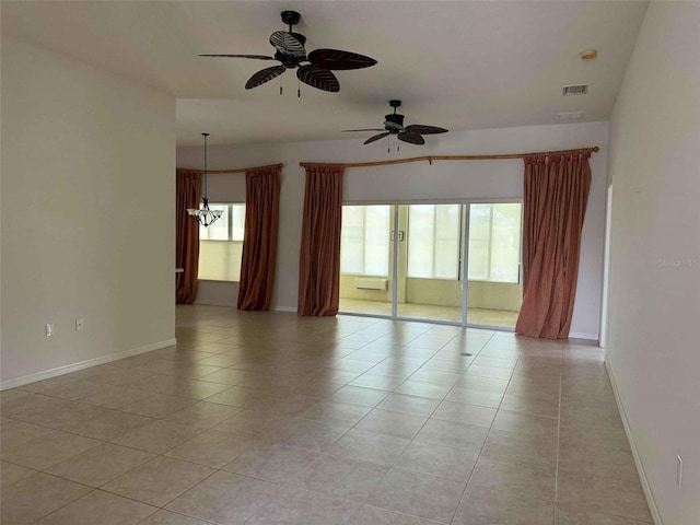 unfurnished room with a wealth of natural light, ceiling fan with notable chandelier, and light tile patterned flooring