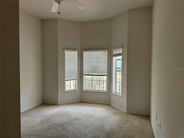 carpeted spare room with a wealth of natural light and ceiling fan