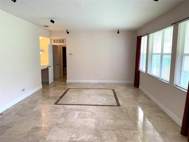 spare room featuring visible vents, baseboards, and a textured ceiling