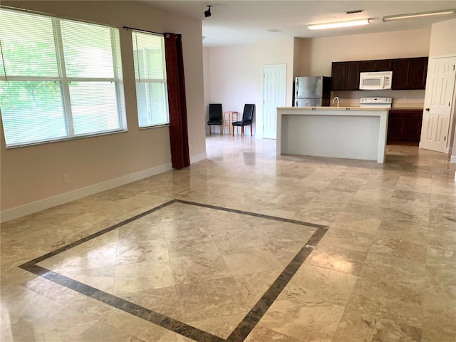 kitchen featuring white microwave, visible vents, baseboards, open floor plan, and freestanding refrigerator