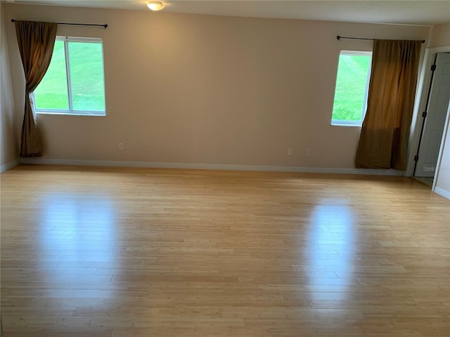 spare room with light wood finished floors, baseboards, and a wealth of natural light