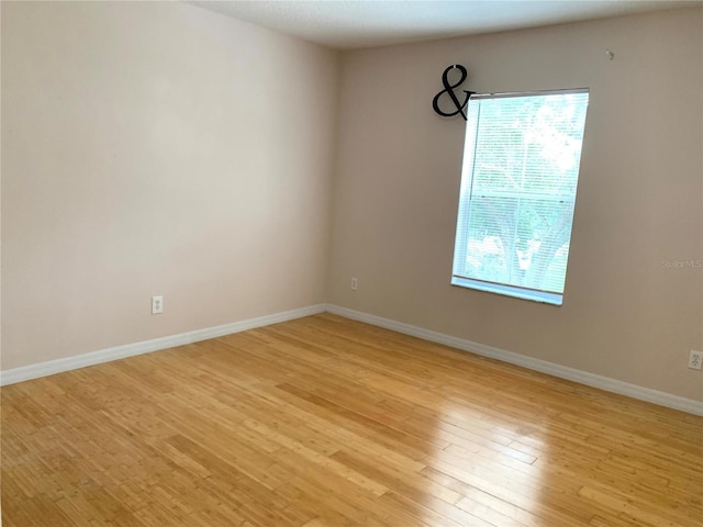 empty room with light wood-style flooring, plenty of natural light, and baseboards