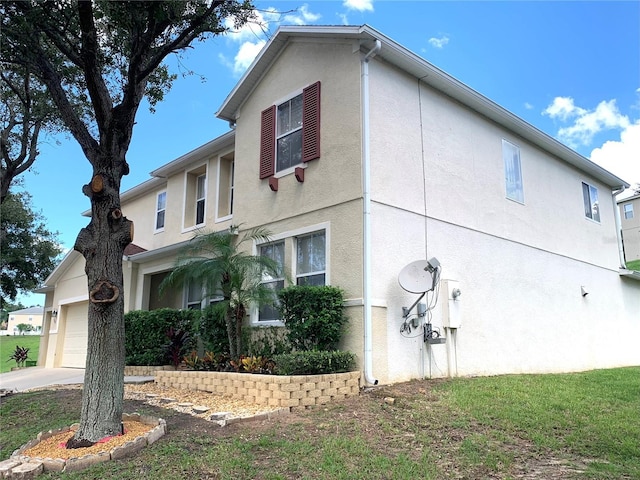 view of property exterior with stucco siding, an attached garage, and a yard