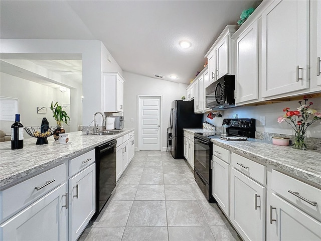 kitchen with black appliances, light stone counters, white cabinetry, and vaulted ceiling