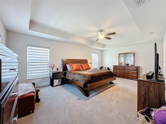 bedroom featuring ceiling fan, a raised ceiling, and light carpet