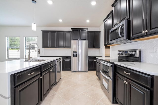 kitchen featuring backsplash, stainless steel appliances, sink, light tile patterned floors, and hanging light fixtures