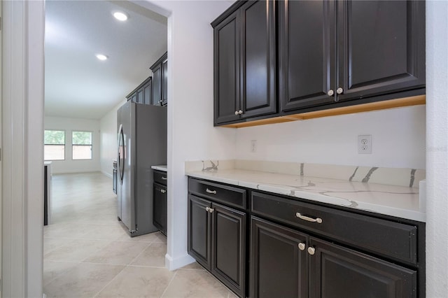 kitchen featuring stainless steel fridge, light stone counters, and light tile patterned flooring