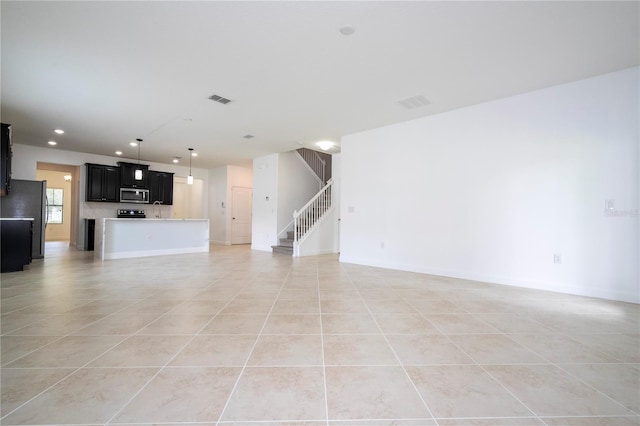 unfurnished living room featuring light tile patterned floors and sink