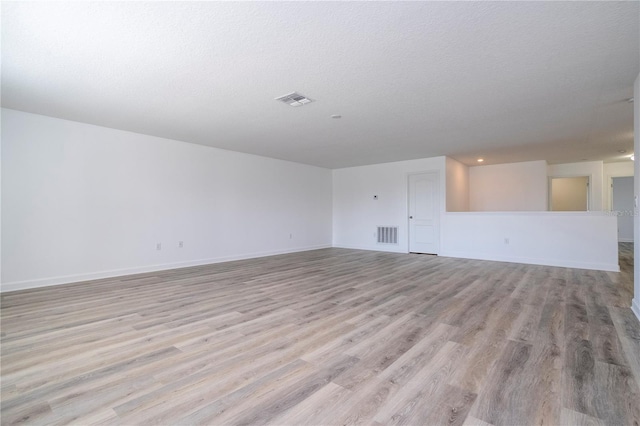 empty room featuring a textured ceiling and light hardwood / wood-style flooring