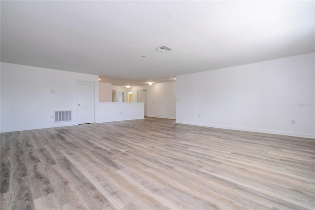 unfurnished living room with a textured ceiling and light hardwood / wood-style flooring